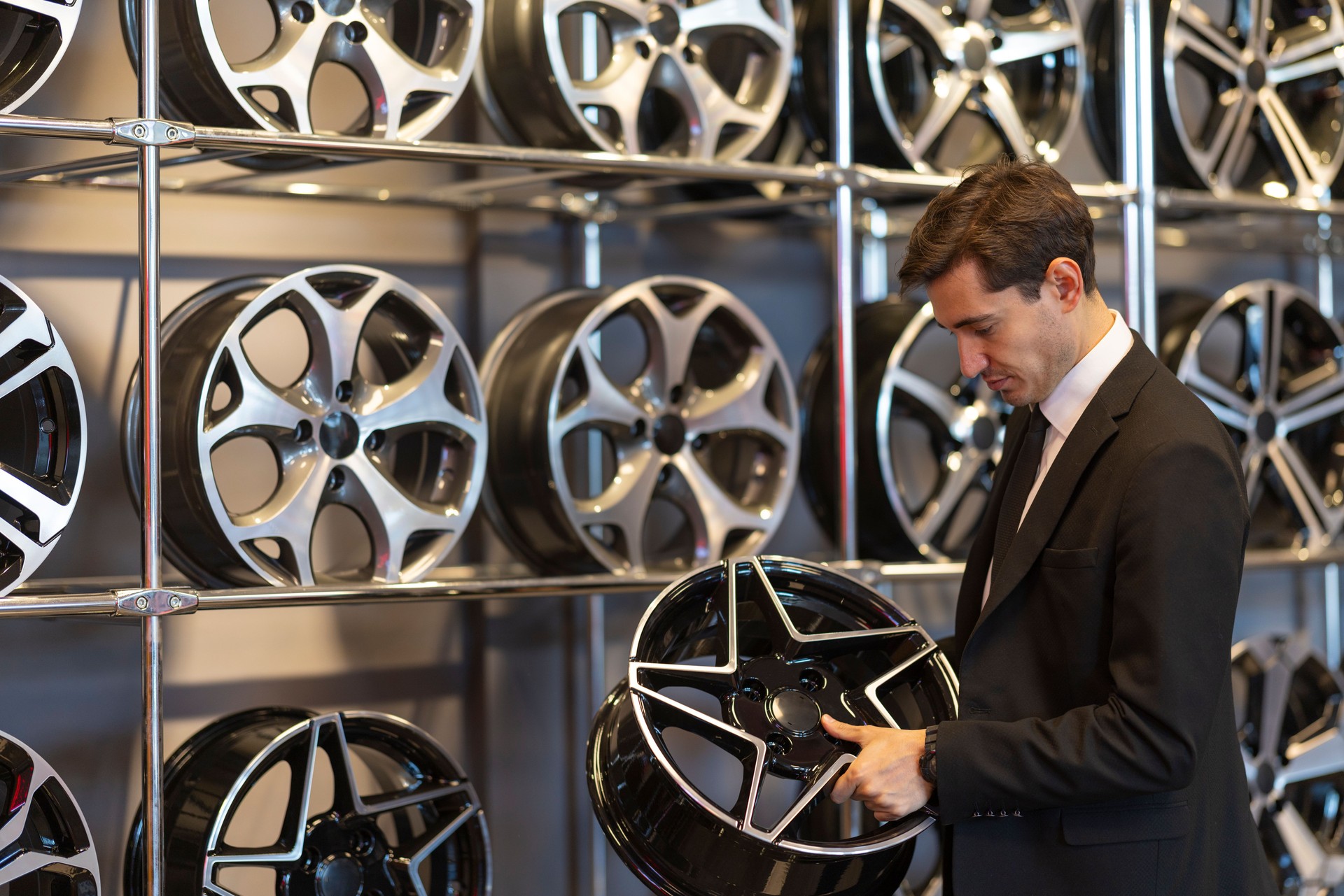 Businessman Inspecting Car Rims in Automotive Store